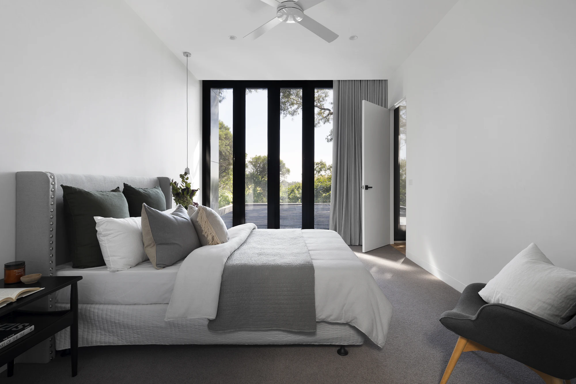 Calm contemporary bedroom with layered grey bedding and floor-to-ceiling glass doors