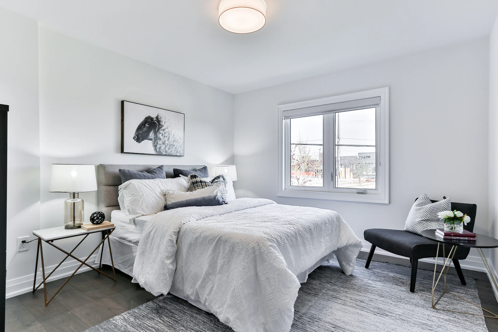 Light-grey bedroom with tufted headboard and accent chair