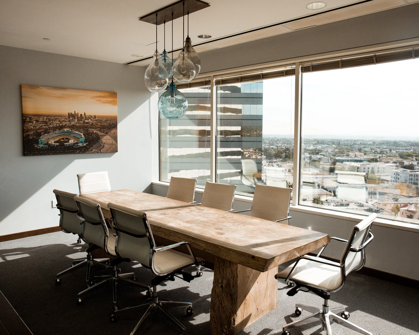 Glass-walled conference room with long timber table and city views