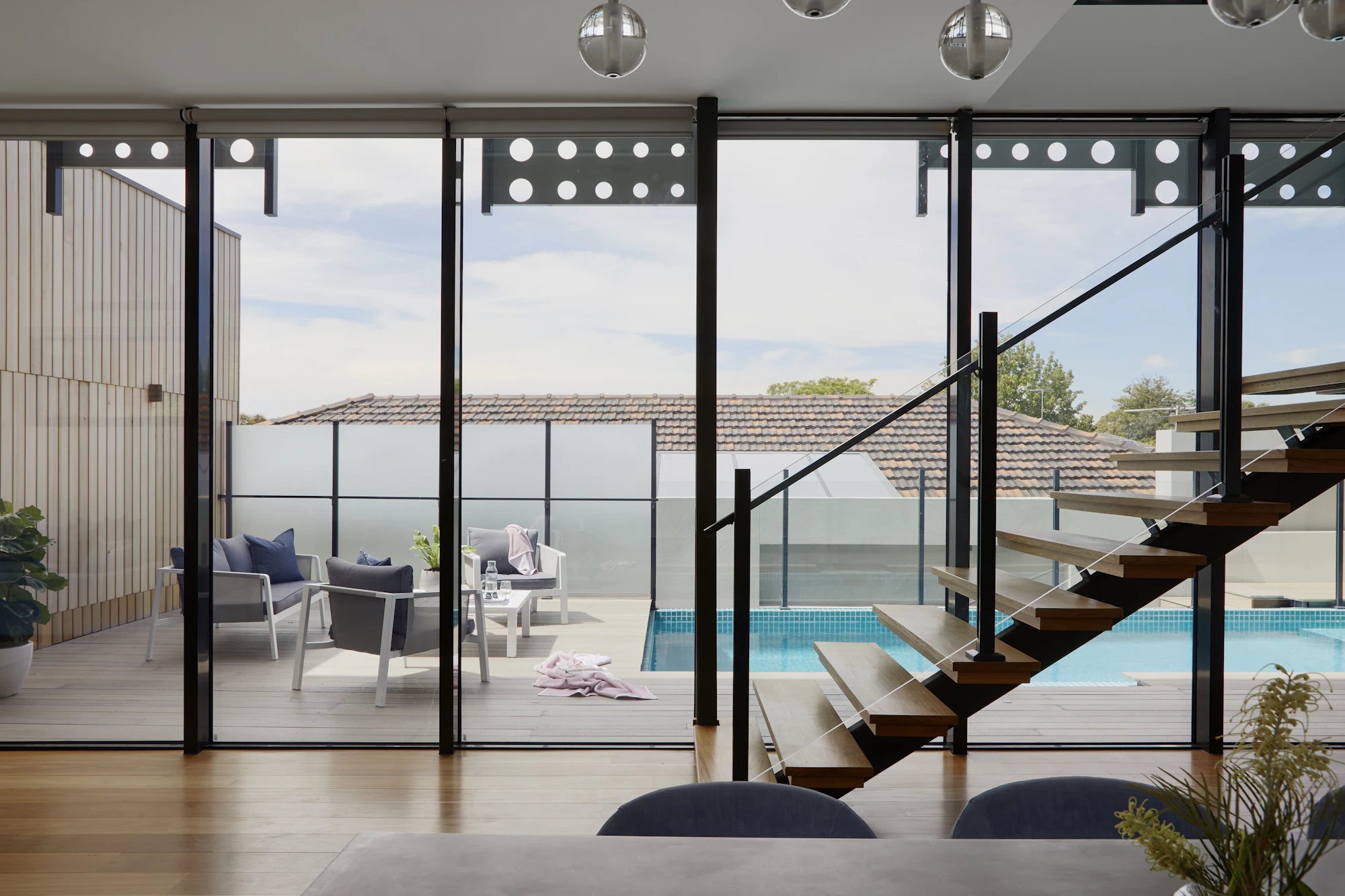 Luxury villa interior with floating staircase, glass walls and poolside view
