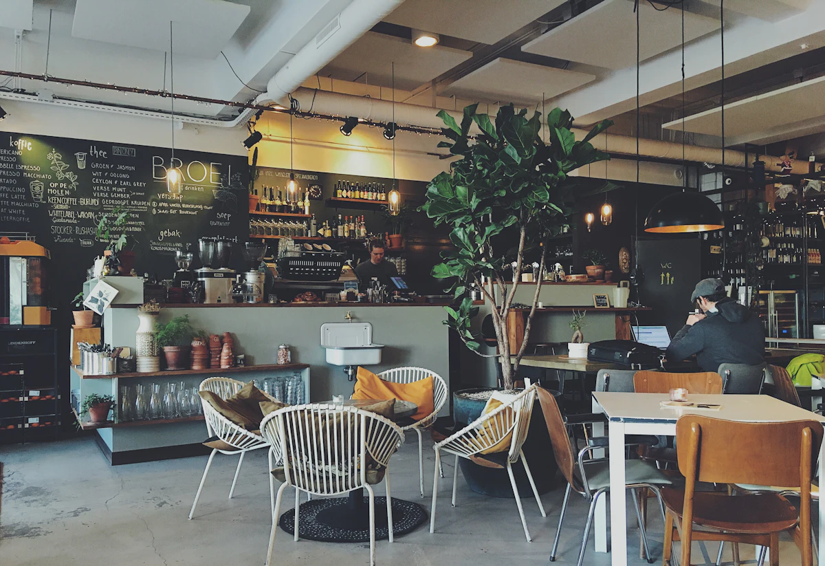 Warm café interior with pendant lights, plants and wooden seating